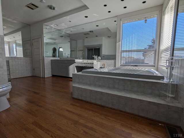 bathroom with wood-type flooring, a bathing tub, vanity, and toilet
