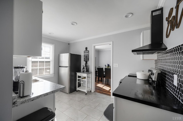 1516 Pierce St, Lynchburg, VA 24501 - kitchen featuring freestanding refrigerator, wall chimney range hood, ornamental molding, light tile patterned floors, and white cabinetry