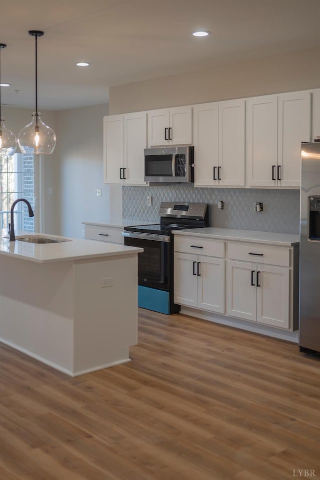 128 Brenleigh Ct Unit 202, Lynchburg, VA 24501 - kitchen with stainless steel appliances, a sink, light wood-style flooring, white cabinets, and decorative backsplash