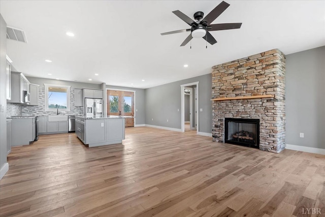4615 Everett Rd, Forest, VA 24551 - unfurnished living room featuring ceiling fan, a fireplace, light wood finished floors, and a sink