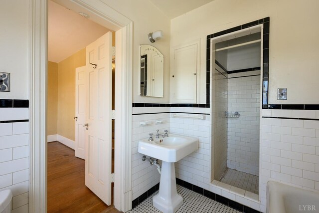 full bath with tile walls, tiled shower, and wood finished floors