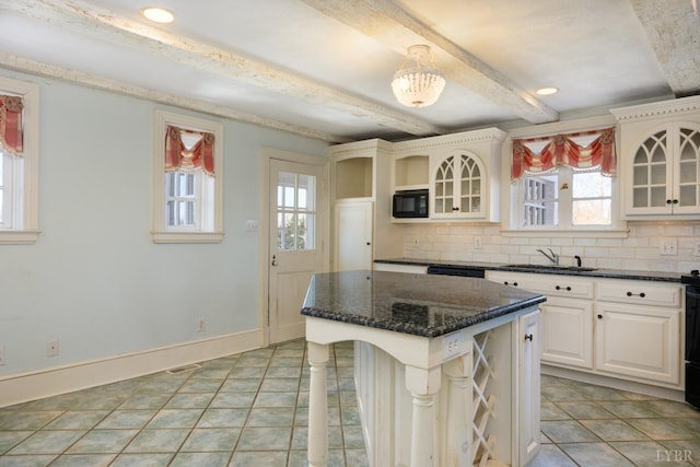 kitchen featuring backsplash, glass insert cabinets, a sink, and black microwave