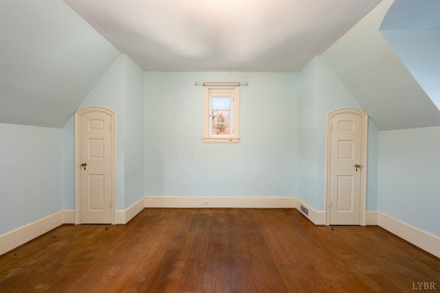 additional living space with vaulted ceiling, baseboards, visible vents, and wood-type flooring