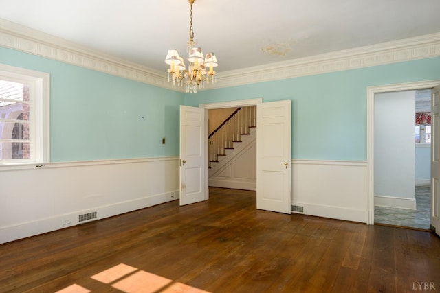 unfurnished dining area with baseboards, dark wood-style flooring, ornamental molding, stairs, and a chandelier