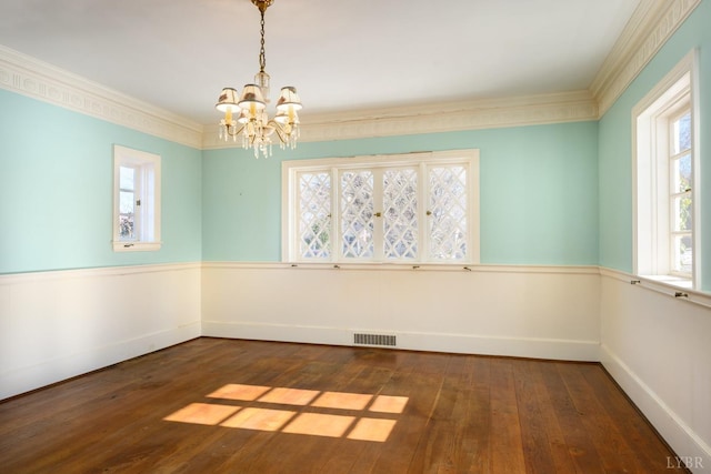 unfurnished dining area featuring crown molding, a chandelier, visible vents, and dark wood-style floors
