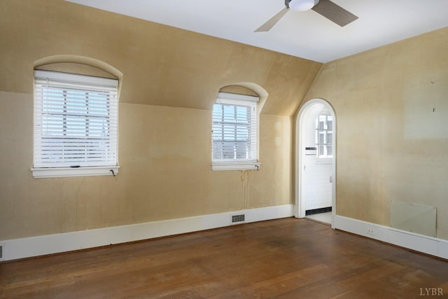 unfurnished room with wood finished floors, visible vents, vaulted ceiling, a ceiling fan, and baseboards