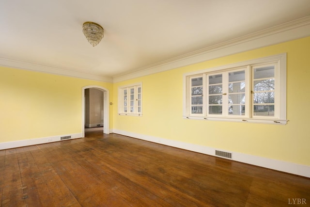 unfurnished room featuring visible vents, baseboards, arched walkways, ornamental molding, and dark wood-style floors