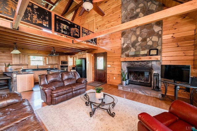2766 Camden Rd, Big Island, VA 24526 - living room with a stone fireplace, wood walls, wood ceiling, beam ceiling, and light hardwood / wood-style flooring