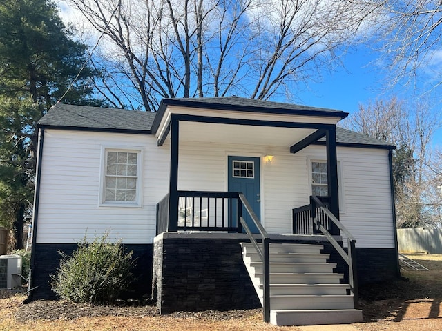 bungalow-style home with cooling unit and roof with shingles