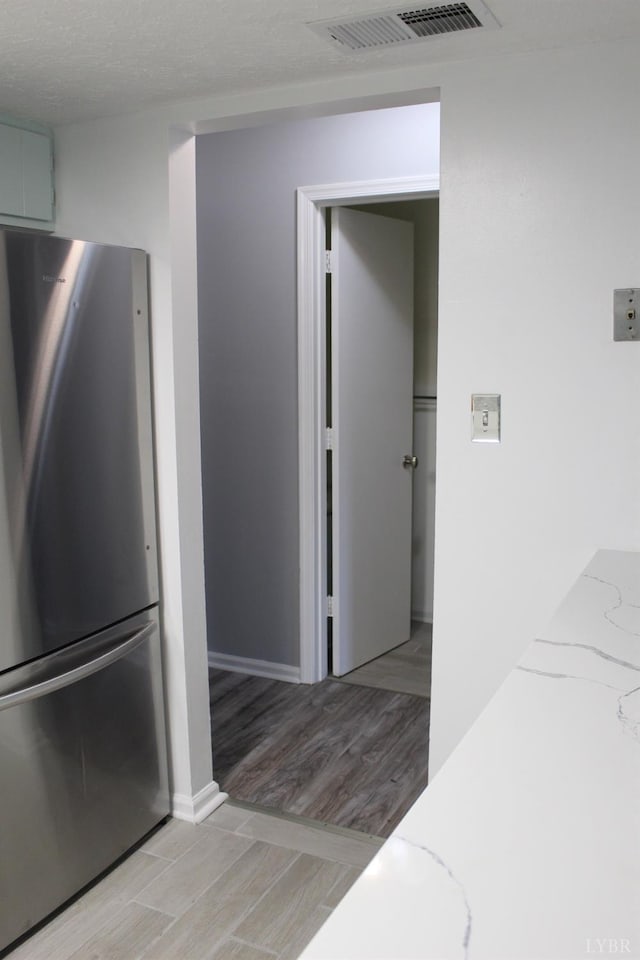 34 Cape Point Ct, Lynchburg, VA 24502 - kitchen with visible vents, freestanding refrigerator, light stone countertops, baseboards, and light wood-style flooring