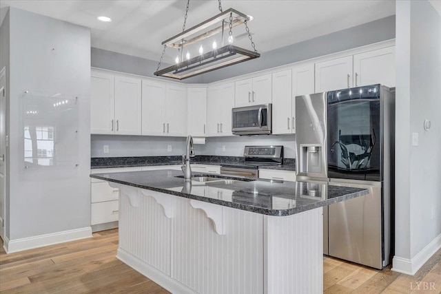 1270 Hupps Hill Ln, Forest, VA 24551 - kitchen featuring appliances with stainless steel finishes, baseboards, white cabinetry, light wood-style flooring, and a kitchen breakfast bar