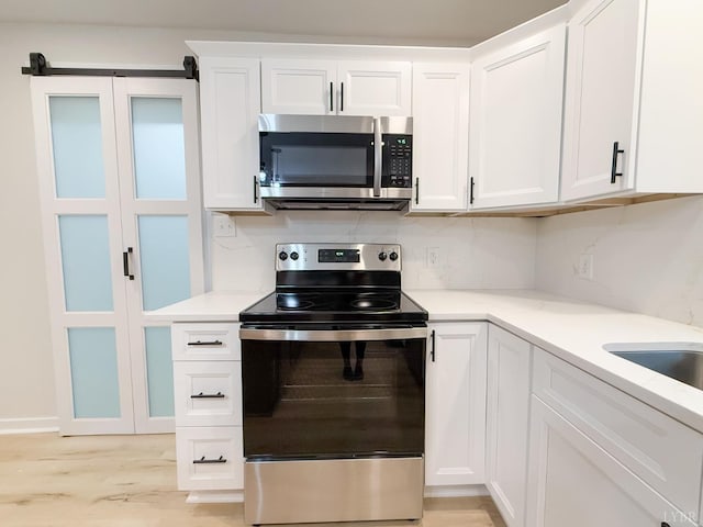 13273 Leesville Rd, Lynch Station, VA 24571 - kitchen with white cabinets, light wood-style floors, light countertops, and appliances with stainless steel finishes