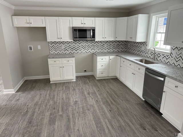 kitchen with a sink, dark wood finished floors, stainless steel appliances, white cabinetry, and ornamental molding