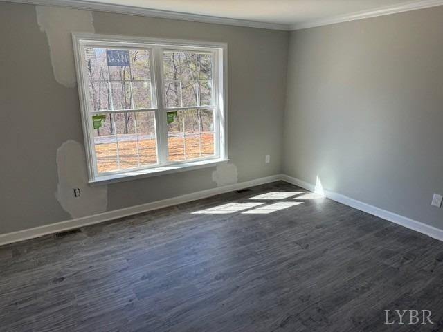 empty room featuring baseboards, ornamental molding, and dark wood finished floors