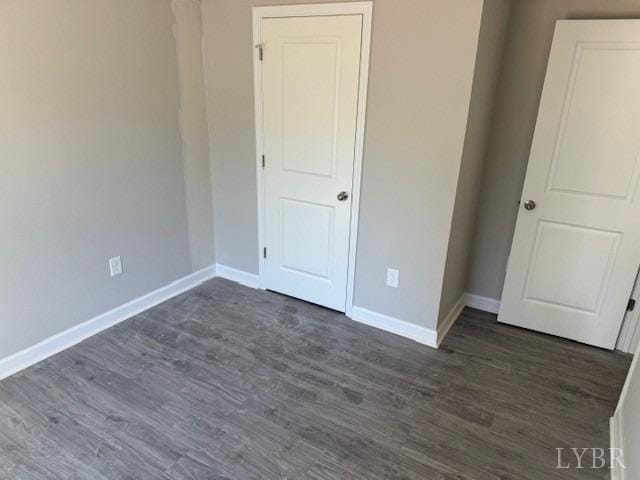 unfurnished bedroom with baseboards and dark wood-style floors
