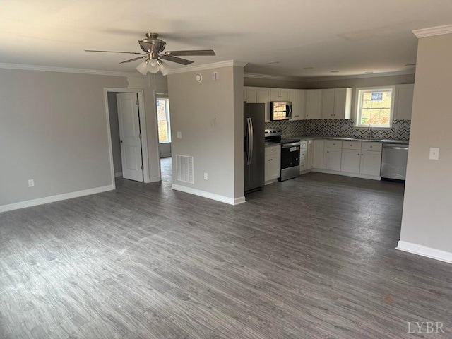 kitchen with stainless steel appliances, open floor plan, and ornamental molding