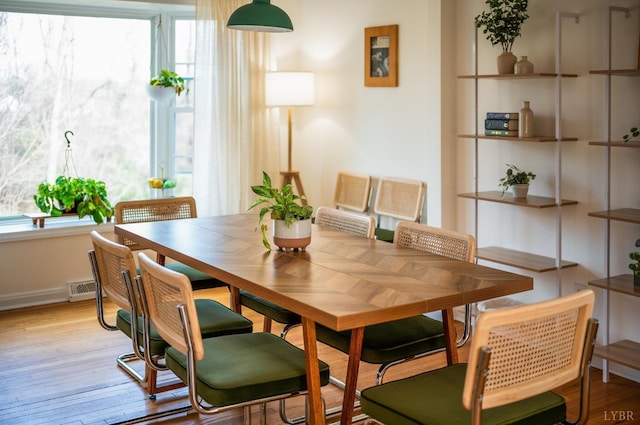 dining area with light wood-type flooring and visible vents