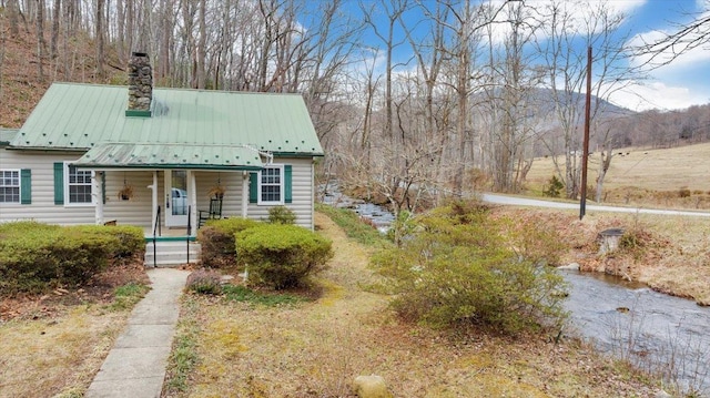 view of front facade featuring a porch, a chimney, metal roof, and a mountain view