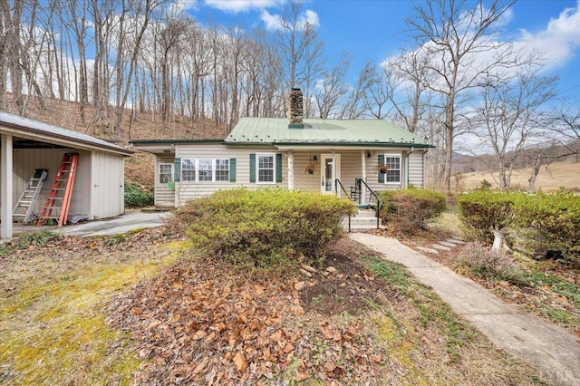 view of front of home with a chimney and metal roof