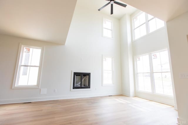 917 Elmwood Ave, Lynchburg, VA 24503 - unfurnished living room with a glass covered fireplace, a towering ceiling, a ceiling fan, light wood-style flooring, and baseboards