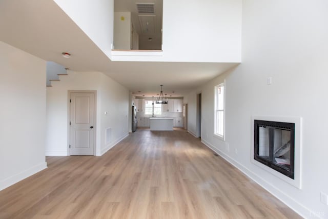 917 Elmwood Ave, Lynchburg, VA 24503 - unfurnished living room with a glass covered fireplace, light wood-style flooring, baseboards, and a chandelier