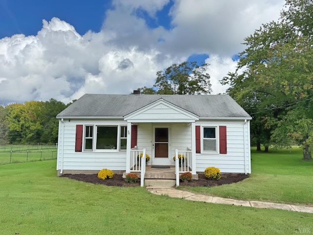 view of front facade featuring a front lawn, fence, and a shingled roof