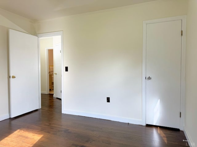 spare room featuring ornamental molding, baseboards, and dark wood finished floors