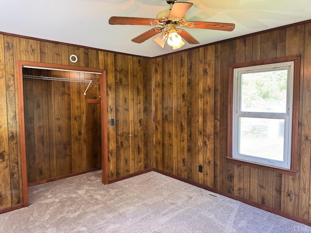 spare room with visible vents, ceiling fan, carpet, and wood walls