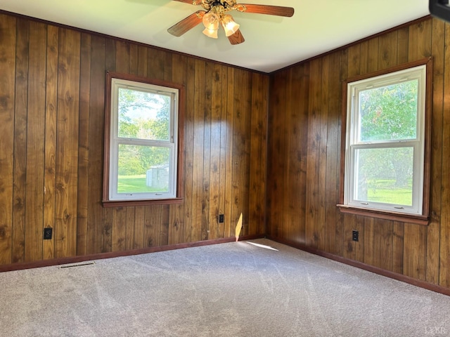 empty room with a wealth of natural light, carpet flooring, visible vents, and ceiling fan