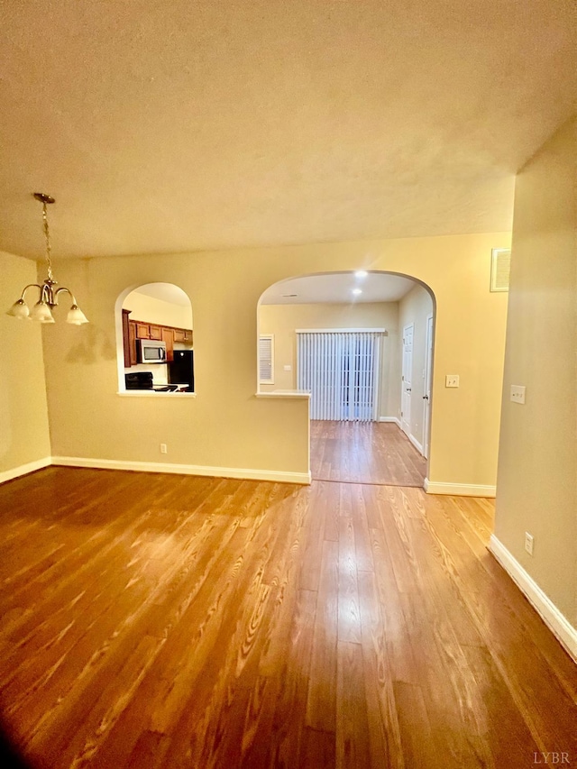 118 Logan Ln, Lynchburg, VA 24502 - unfurnished living room featuring hardwood / wood-style flooring, a chandelier, a textured ceiling, and arched walkways