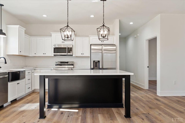 2802 Liberty Chapel Rd, Appomattox, VA 24522 - kitchen featuring appliances with stainless steel finishes, a kitchen island, light countertops, light wood finished floors, and white cabinetry