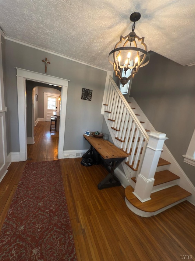 318 Westover Blvd, Lynchburg, VA 24501 - stairway featuring a textured ceiling, baseboards, arched walkways, wood-type flooring, and a notable chandelier