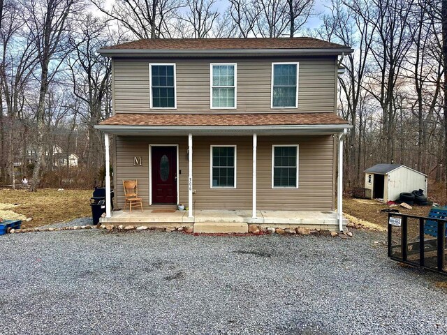 view of front of home with covered porch, gravel driveway, and an outdoor structure
