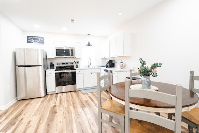 1582 Venturous Trl, Goode, VA 24556 - kitchen featuring light countertops, appliances with stainless steel finishes, hanging light fixtures, light wood-style flooring, and white cabinets