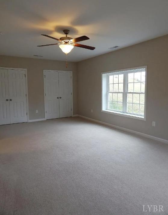 289 Todd Ln, Madison Heights, VA 24572 - unfurnished bedroom featuring light carpet, baseboards, visible vents, two closets, and ceiling fan