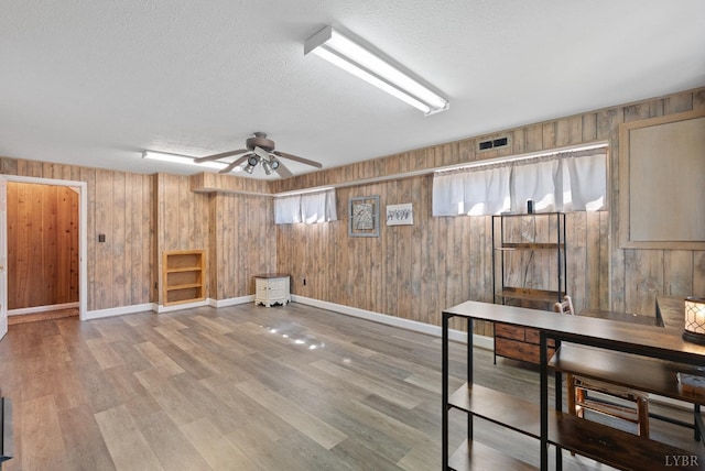 337 Virginia Ave, Appomattox, VA 24522 - basement featuring a textured ceiling, wooden walls, ceiling fan, wood finished floors, and baseboards