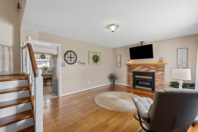 337 Virginia Ave, Appomattox, VA 24522 - living area with wood finished floors, stairs, a brick fireplace, and baseboards