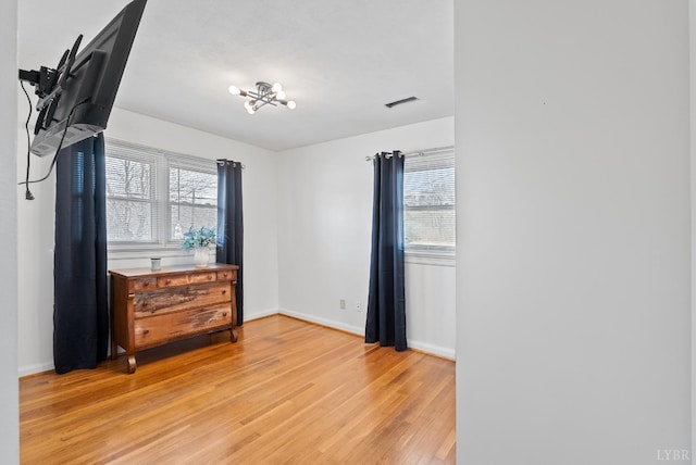 337 Virginia Ave, Appomattox, VA 24522 - unfurnished bedroom with light wood-style flooring, multiple windows, baseboards, and a chandelier