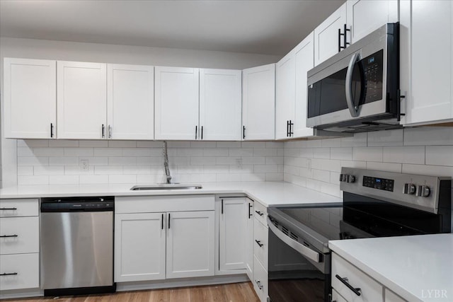 623 Monroe St, Lynchburg, VA 24504 - kitchen with stainless steel appliances, a sink, light countertops, white cabinetry, and light wood-style floors