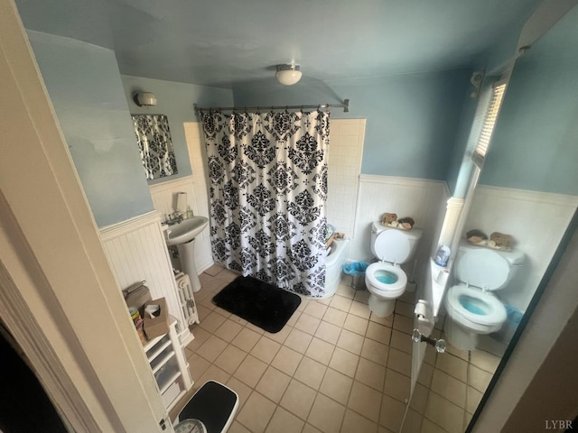 full bathroom with toilet, curtained shower, a wainscoted wall, and tile patterned floors