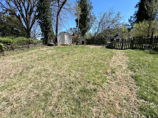 view of yard featuring fence, a storage unit, and an outbuilding