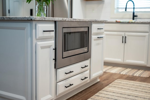 706 Elmwood Ave, Lynchburg, VA 24503 - room details with stainless steel microwave, a sink, wood finished floors, white cabinets, and light stone countertops