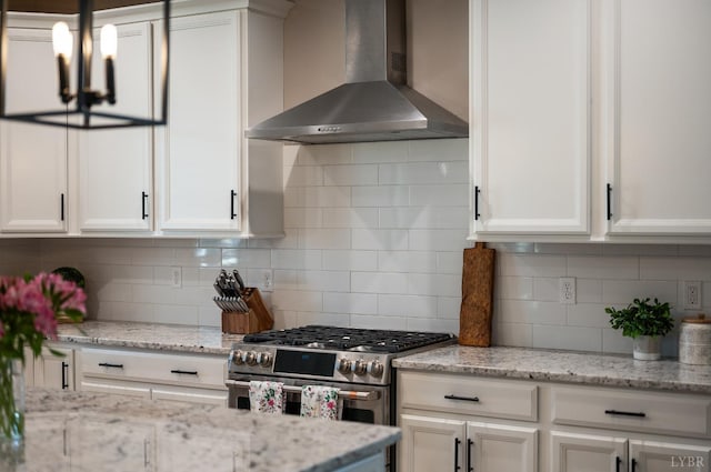 706 Elmwood Ave, Lynchburg, VA 24503 - kitchen featuring wall chimney exhaust hood, double oven range, white cabinetry, decorative backsplash, and a chandelier