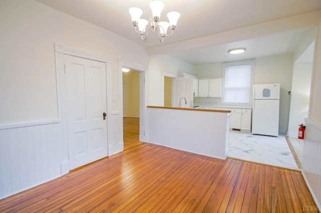 226 Denver Ave, Lynchburg, VA 24503 - kitchen featuring a peninsula, an inviting chandelier, freestanding refrigerator, white cabinets, and light wood-type flooring