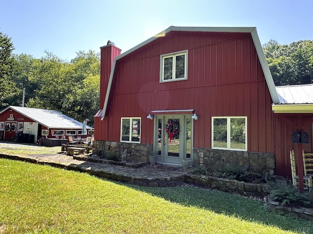 view of front of home with stone siding, a barn, and a front yard