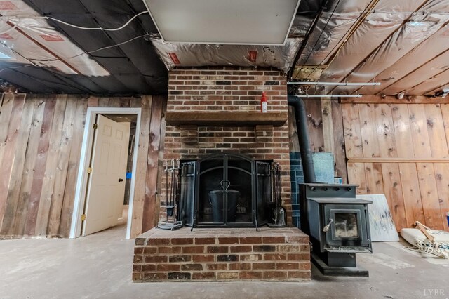 1553 Old Stage Rd, Amherst, VA 24521 - unfurnished living room featuring wooden walls, unfinished concrete floors, a wood stove, and a fireplace