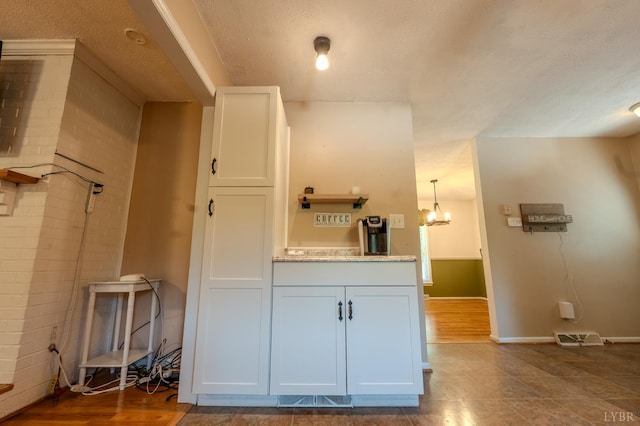 1553 Old Stage Rd, Amherst, VA 24521 - kitchen featuring white cabinetry, a chandelier, a textured ceiling, and light stone countertops