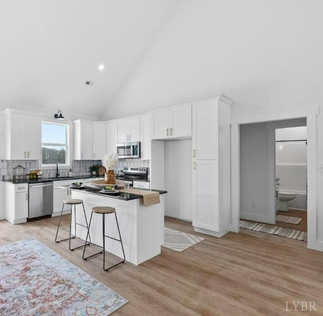 3470 Double Bridges Rd, Spout Spring, VA 24593 - kitchen featuring appliances with stainless steel finishes, white cabinetry, a sink, tasteful backsplash, and high vaulted ceiling