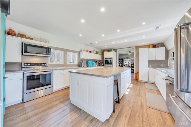 3554 Leffel Rd, Roanoke, VA 24018 - kitchen featuring appliances with stainless steel finishes, a center island, light wood-style floors, light countertops, and white cabinetry