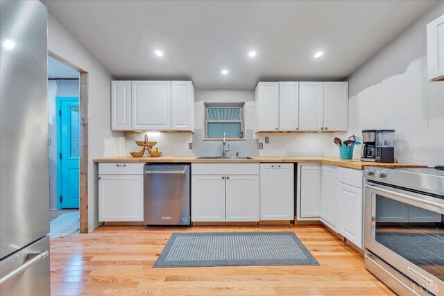 3554 Leffel Rd, Roanoke, VA 24018 - kitchen with appliances with stainless steel finishes, a sink, white cabinets, light wood-style floors, and recessed lighting